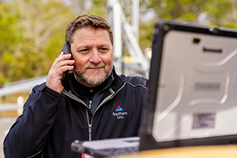worker using phone and laptop